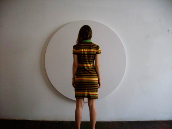 simonetta from the back wearing a striped dress in front of a white round canvas